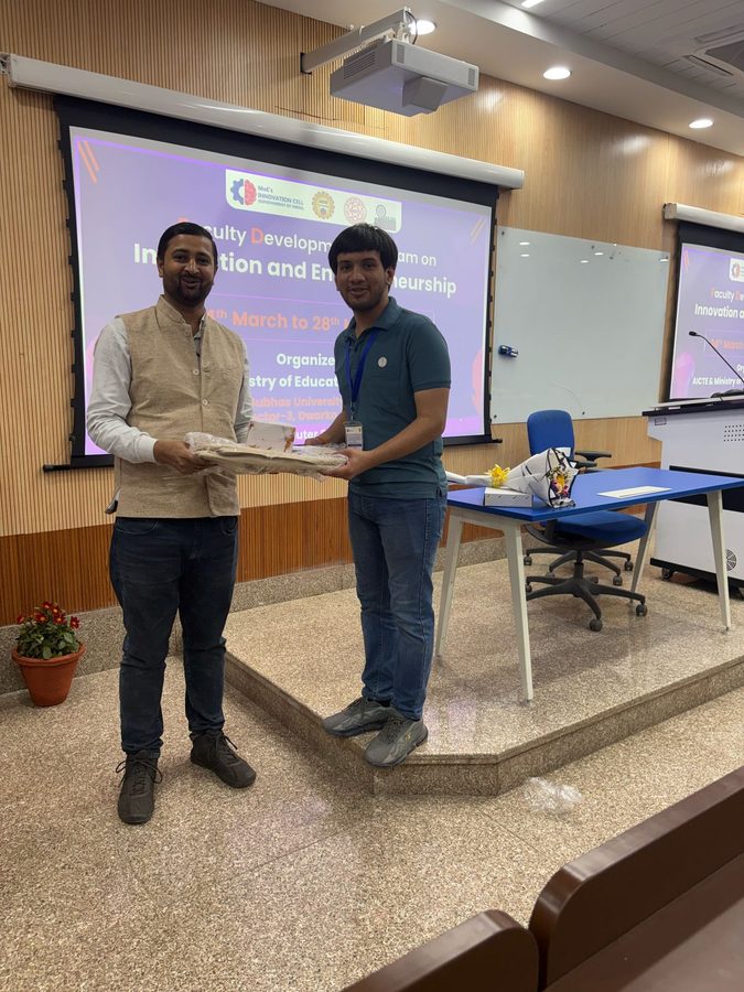 Presenting a memento to a speaker on stage at the Faculty Development Programme on Innovation and Entrepreneurship