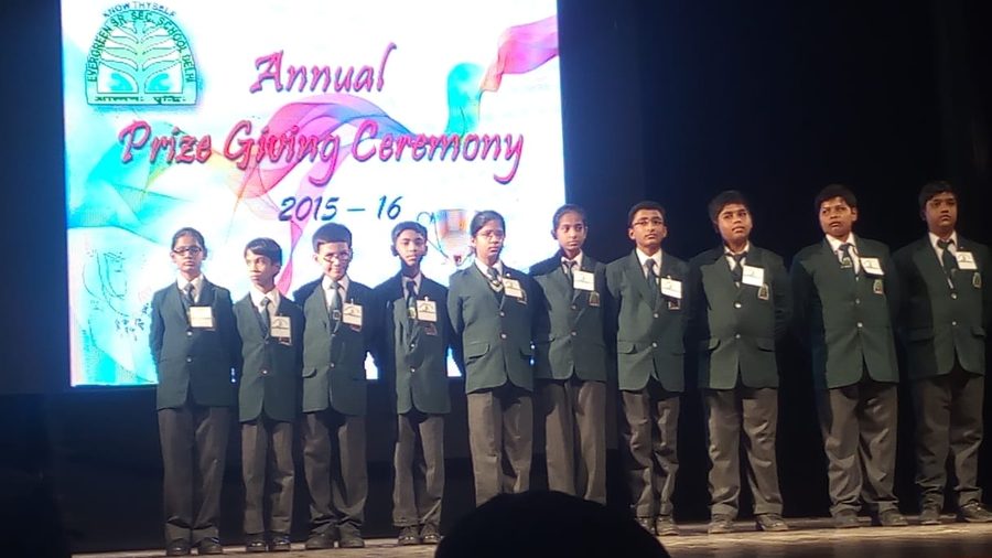 A line of school students in green blazers on stage at an annual prize giving ceremony
