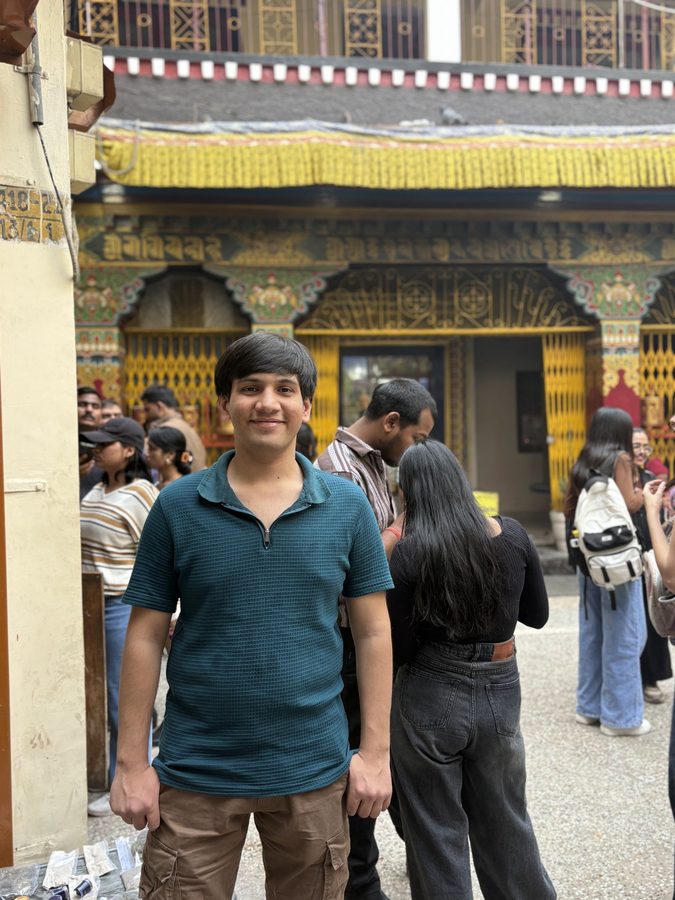 Standing outside a carved temple courtyard hung with marigold garlands
